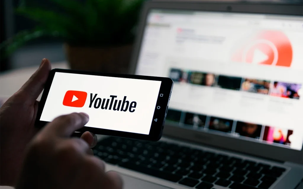 Persona usando YouTube en móvil y portátil.