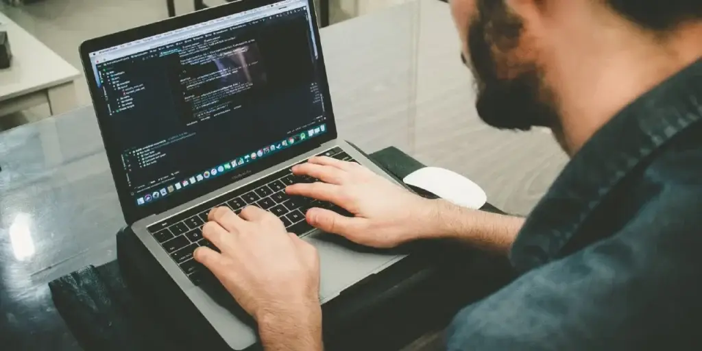 Programador trabajando en laptop con código visible