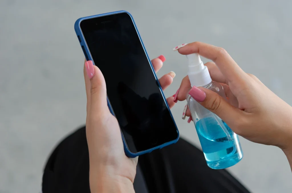 Persona limpiando móvil con solución desinfectante